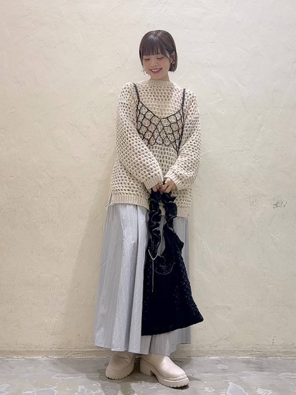 ブラック系のベスト、ベージュ系のブーツ、ブラック系のトートバッグを着用したレディースの冬コーディネートの2枚目の写真