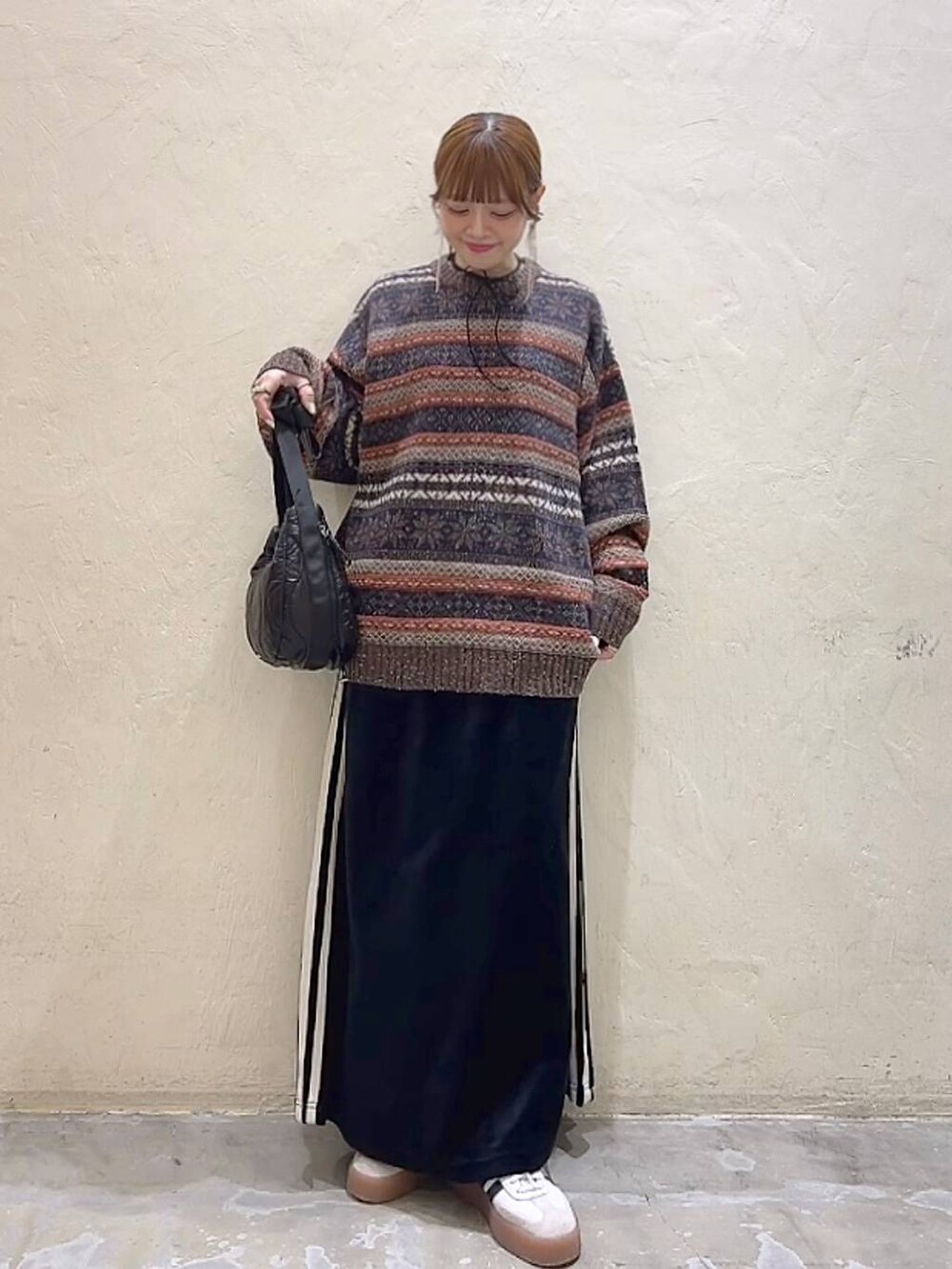 ブラック系のショルダーバッグ、ブラウン系のニット/セーター、ブラック系のスカートを着用したレディースの冬コーディネートの8枚目の写真