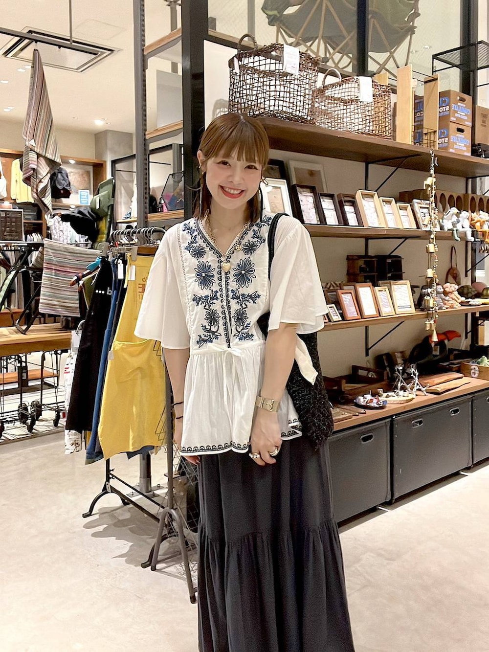 グレー系のスカート、ホワイト系のシャツ/ブラウス、ブラック系のトートバッグを着用したレディースの春コーディネートの2枚目の写真