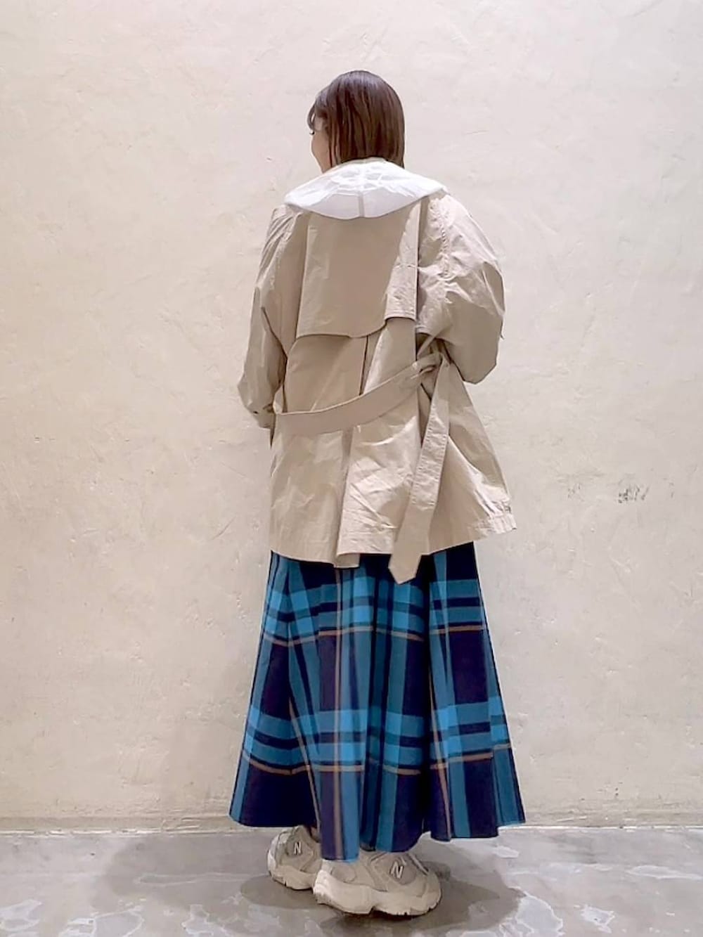 ベージュ系のトレンチコート、ベージュ系のキャミソール、ホワイト系のマウンテンパーカーを着用したレディースの春コーディネートの5枚目の写真