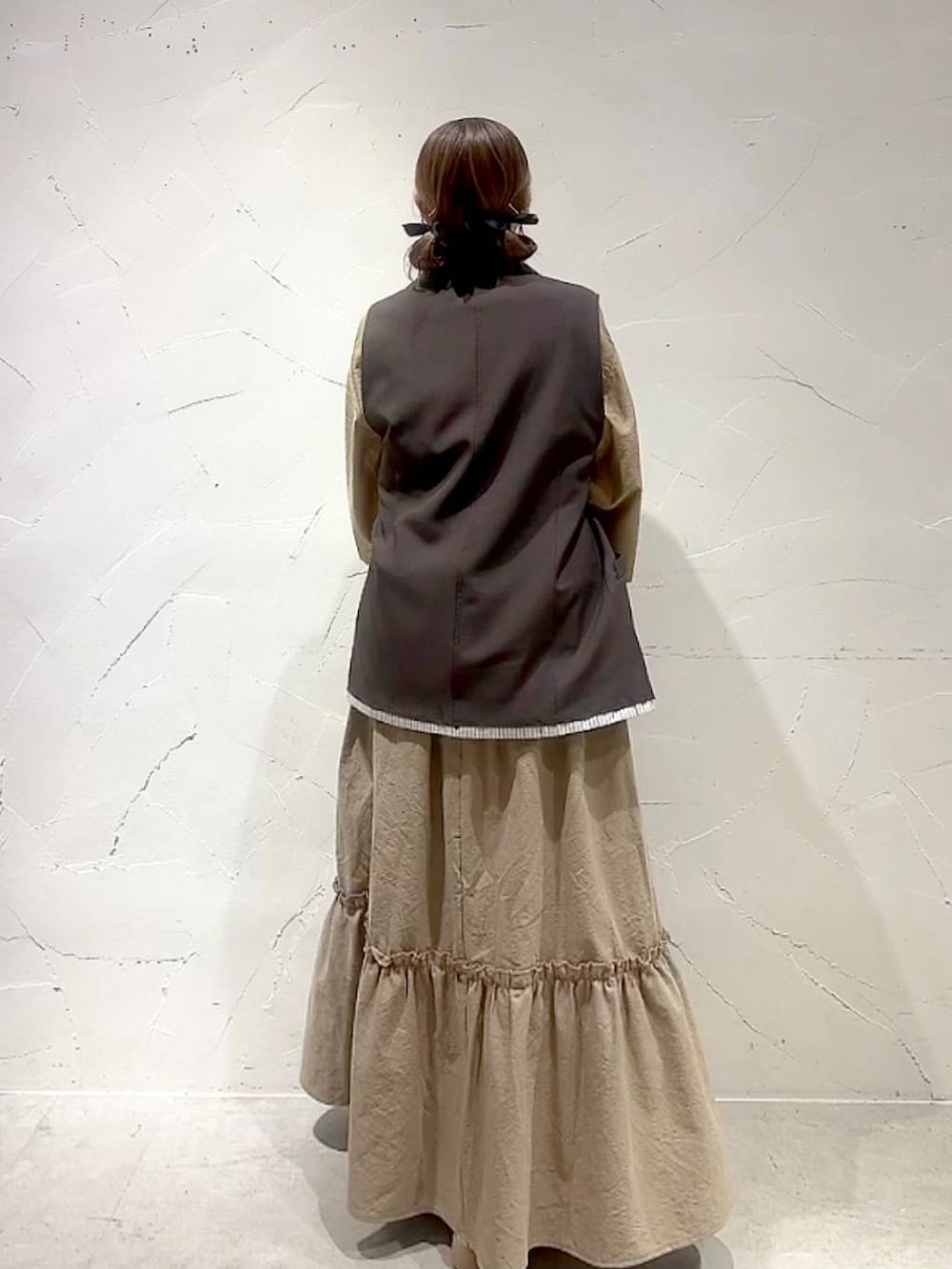 イエロー系のスカート、ブラウン系のベストを着用したレディースの夏コーディネートの7枚目の写真