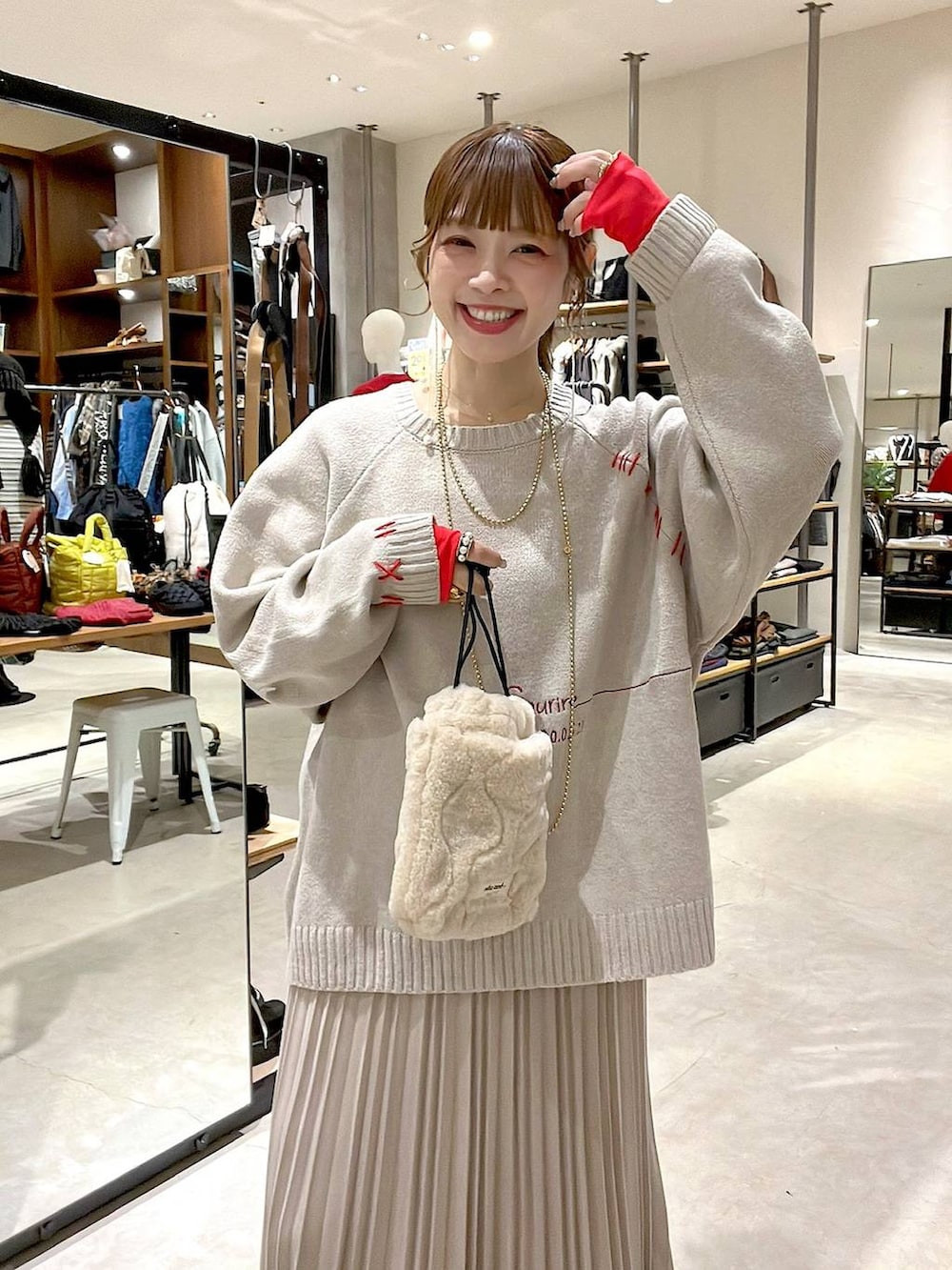 ベージュ系のスカート、ベージュ系のショルダーバッグ、イエロー系のネックレスを着用したレディースの秋コーディネートの2枚目の写真