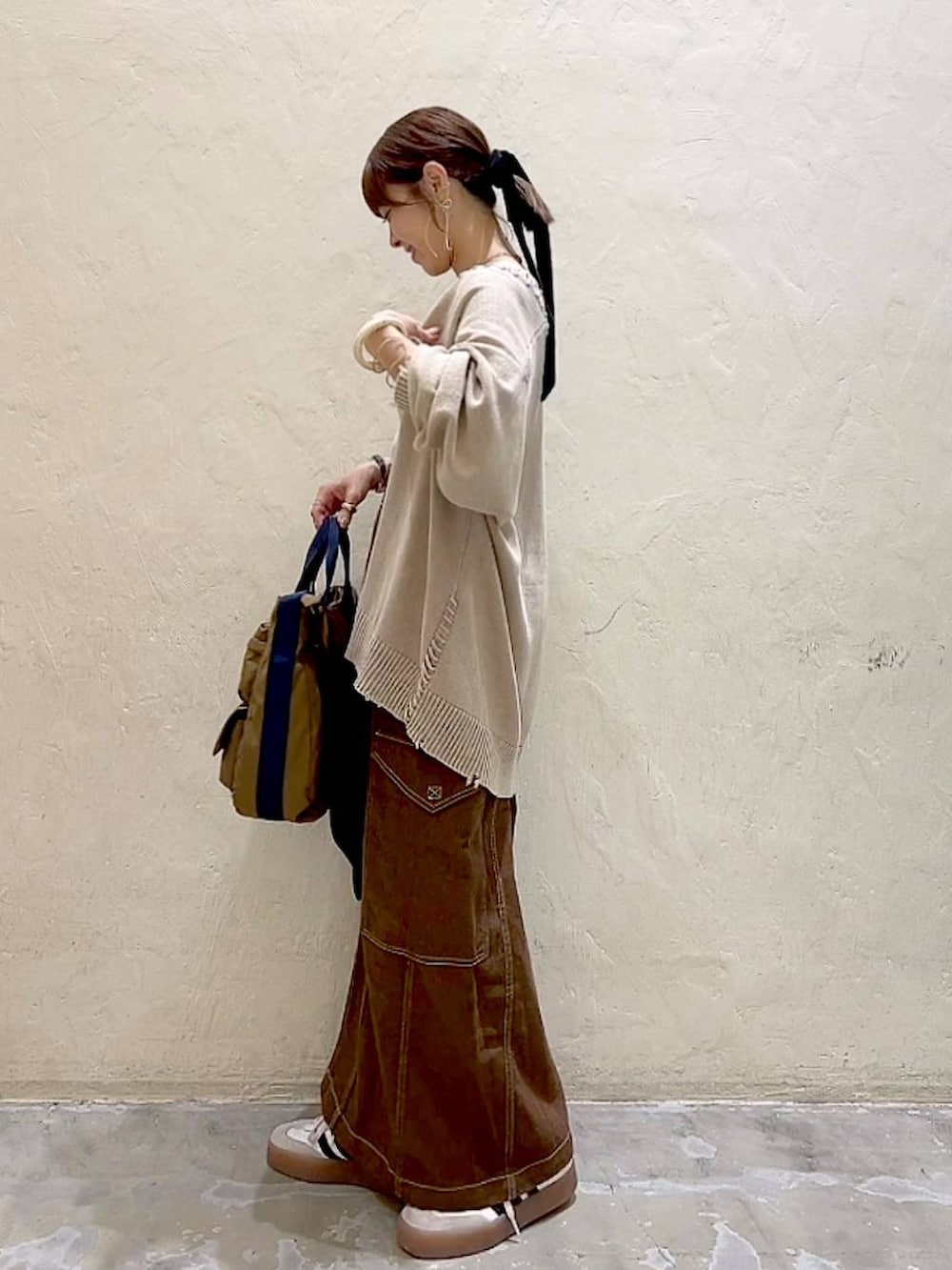 ベージュ系のカーディガン/ボレロ、ブラウン系のスカート、ブラウン系のトートバッグを着用したレディースの秋コーディネートの6枚目の写真