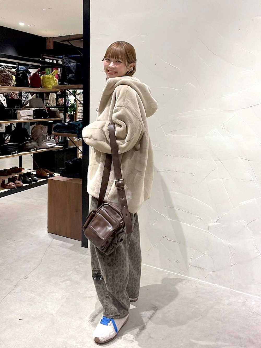 ブラウン系のデニムパンツ、ベージュ系のブルゾン、ブラウン系のショルダーバッグを着用したレディースの冬コーディネートの4枚目の写真