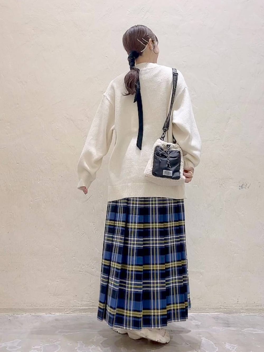 ブルー系のスカート、ホワイト系のニット/セーター、ベージュ系のショルダーバッグを着用したレディースの冬コーディネートの4枚目の写真