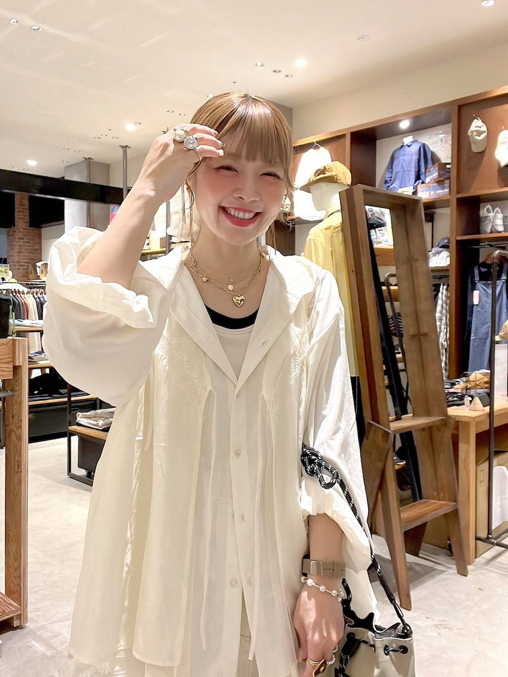 グレー系のショルダーバッグ、ホワイト系のシャツ/ブラウス、ホワイト系のベストを着用したレディースの春コーディネートの5枚目の写真