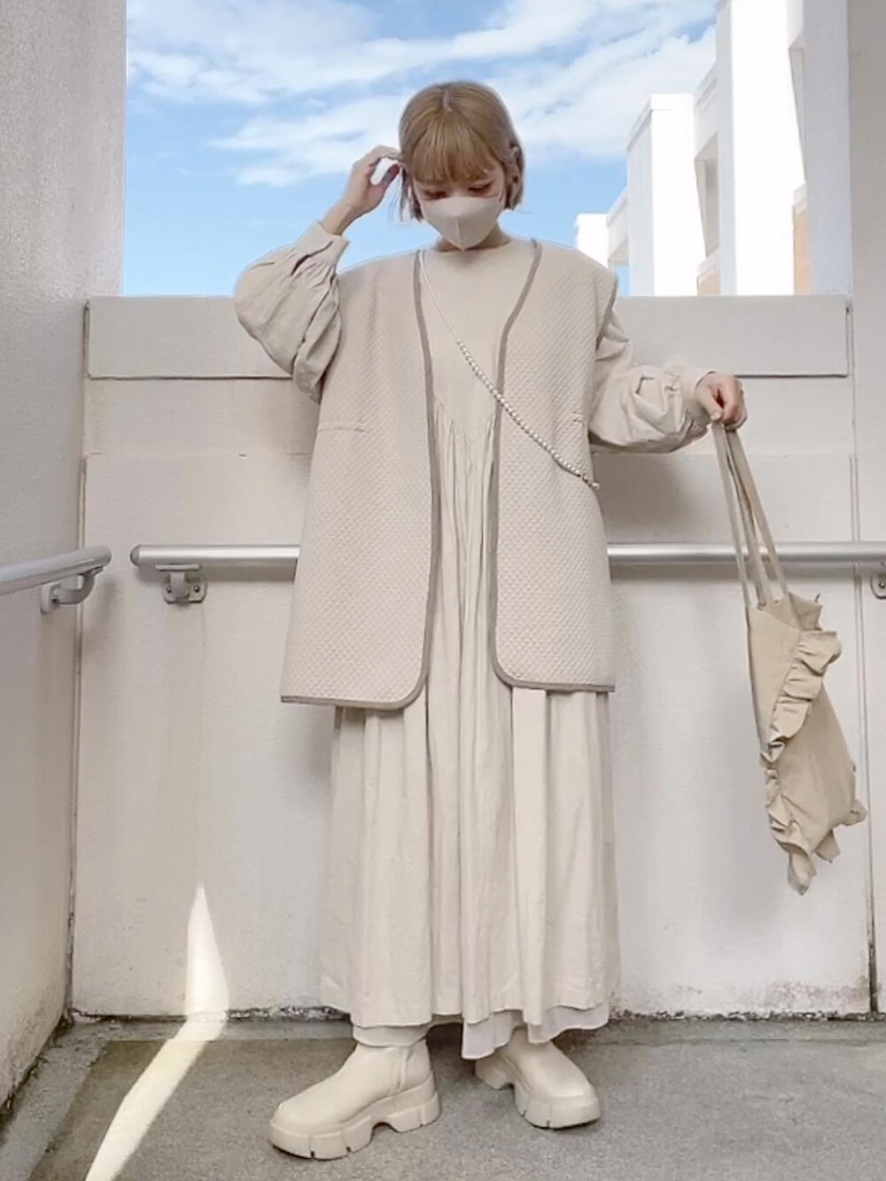 ベージュ系のベスト、ベージュ系のワンピース、ホワイト系のブーツを着用したレディースの冬コーディネートの3枚目の写真