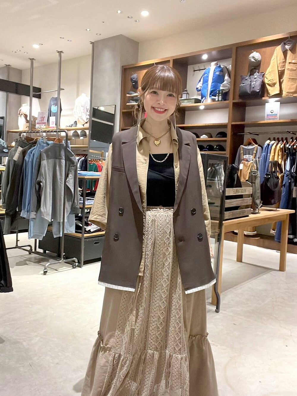 イエロー系のスカート、ブラウン系のベストを着用したレディースの夏コーディネートの9枚目の写真