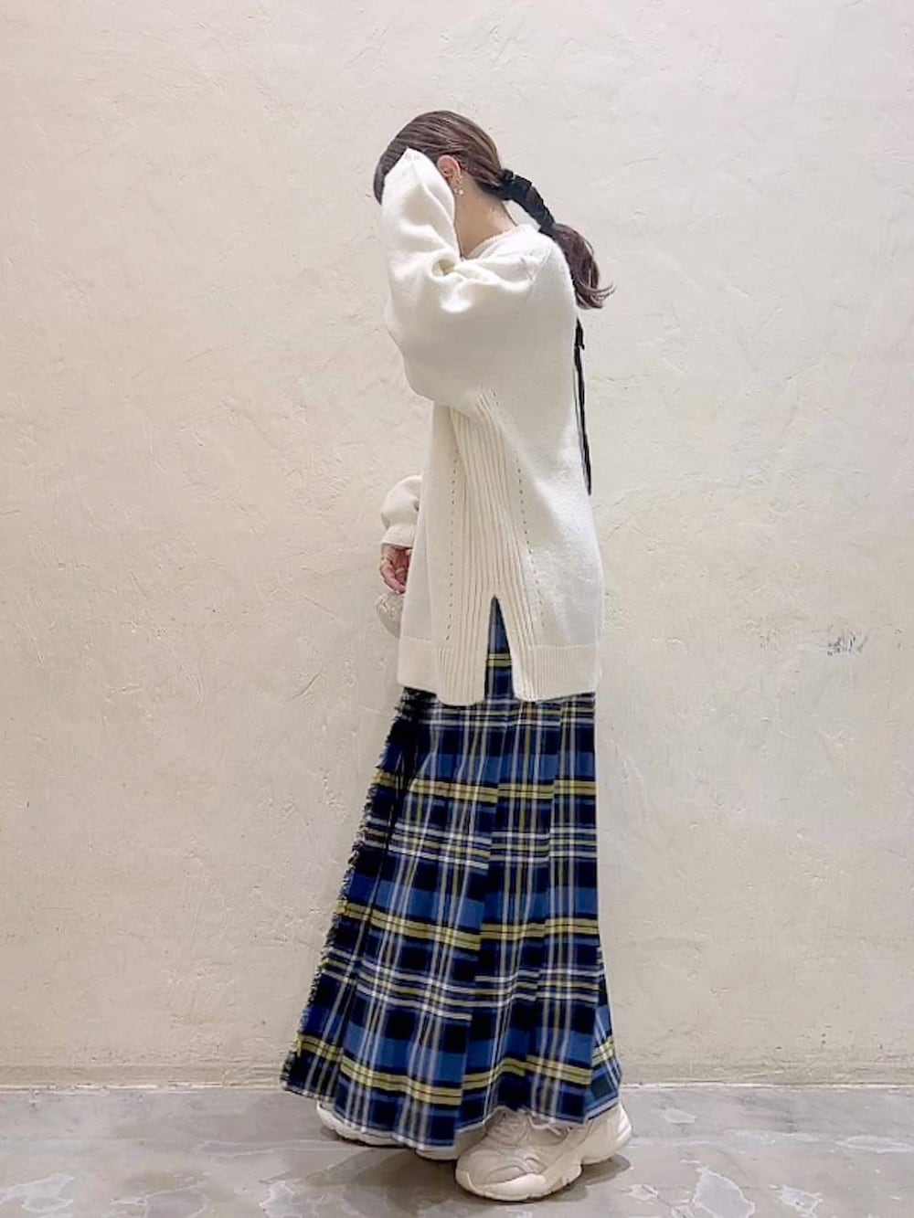 ブルー系のスカート、ホワイト系のニット/セーター、ベージュ系のショルダーバッグを着用したレディースの冬コーディネートの5枚目の写真