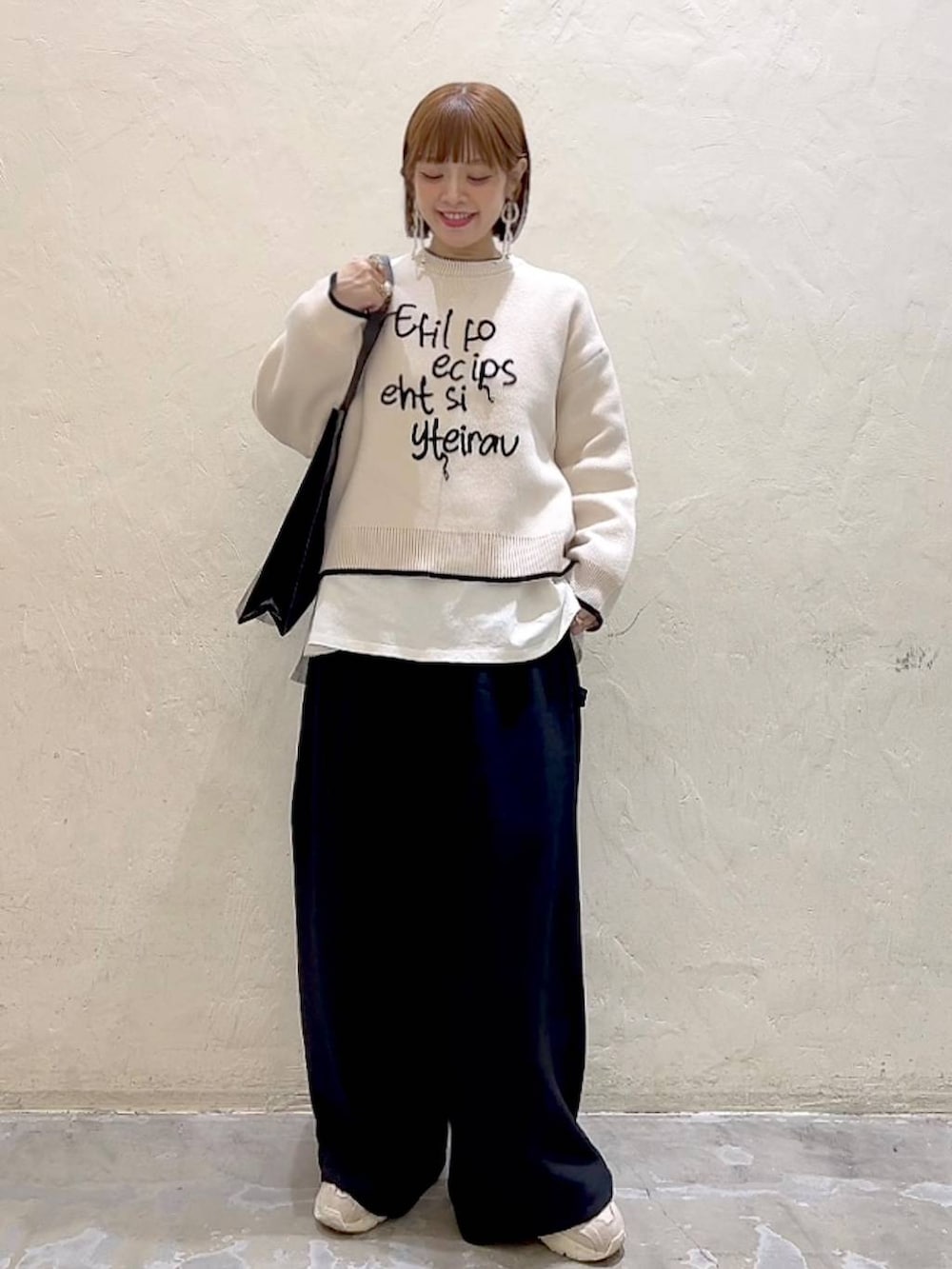 ホワイト系のTシャツ/カットソー、ブラック系のその他パンツ、ベージュ系のニット/セーターを着用したレディースの冬コーディネートの6枚目の写真