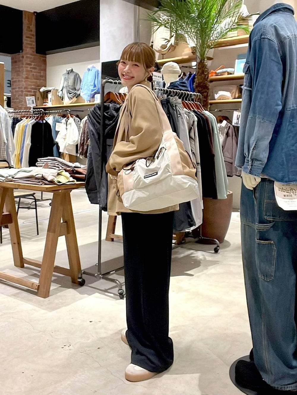 ベージュ系のトートバッグ、ブラック系のサロペット/オーバーオール、ホワイト系のTシャツ/カットソーを着用したレディースの冬コーディネートの3枚目の写真