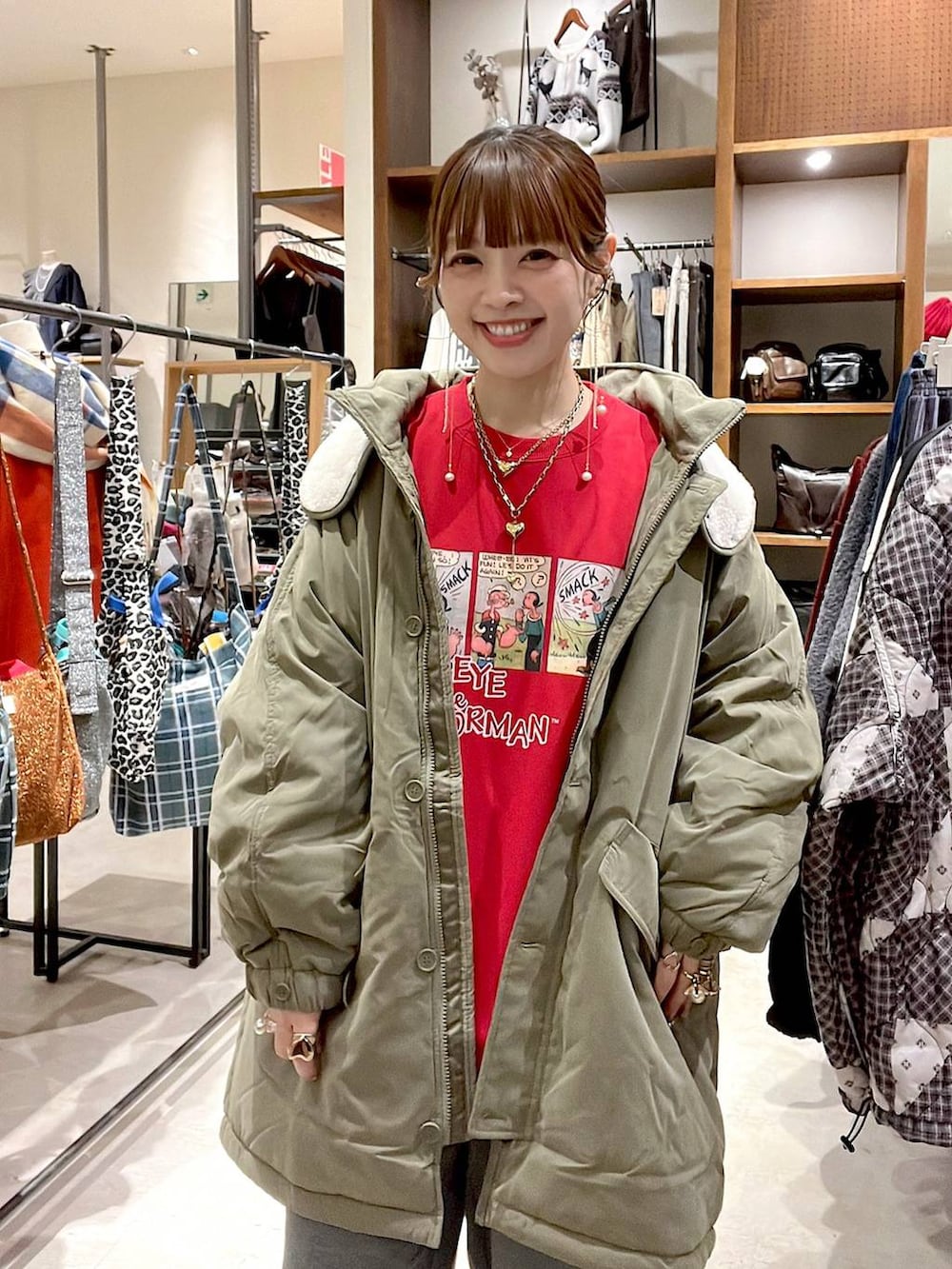 グリーン系のブルゾン、グレー系のその他パンツ、レッド系のスウェットを着用したレディースの冬コーディネートの2枚目の写真