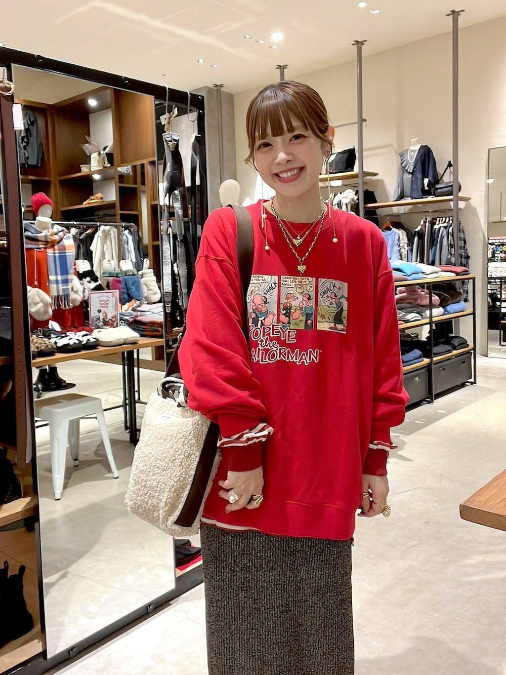 レッド系のTシャツ/カットソー、ホワイト系のスカート、ベージュ系のトートバッグを着用したレディースの冬コーディネートの4枚目の写真