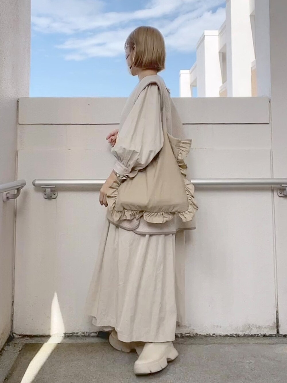 ベージュ系のベスト、ベージュ系のワンピース、ホワイト系のブーツを着用したレディースの冬コーディネートの2枚目の写真