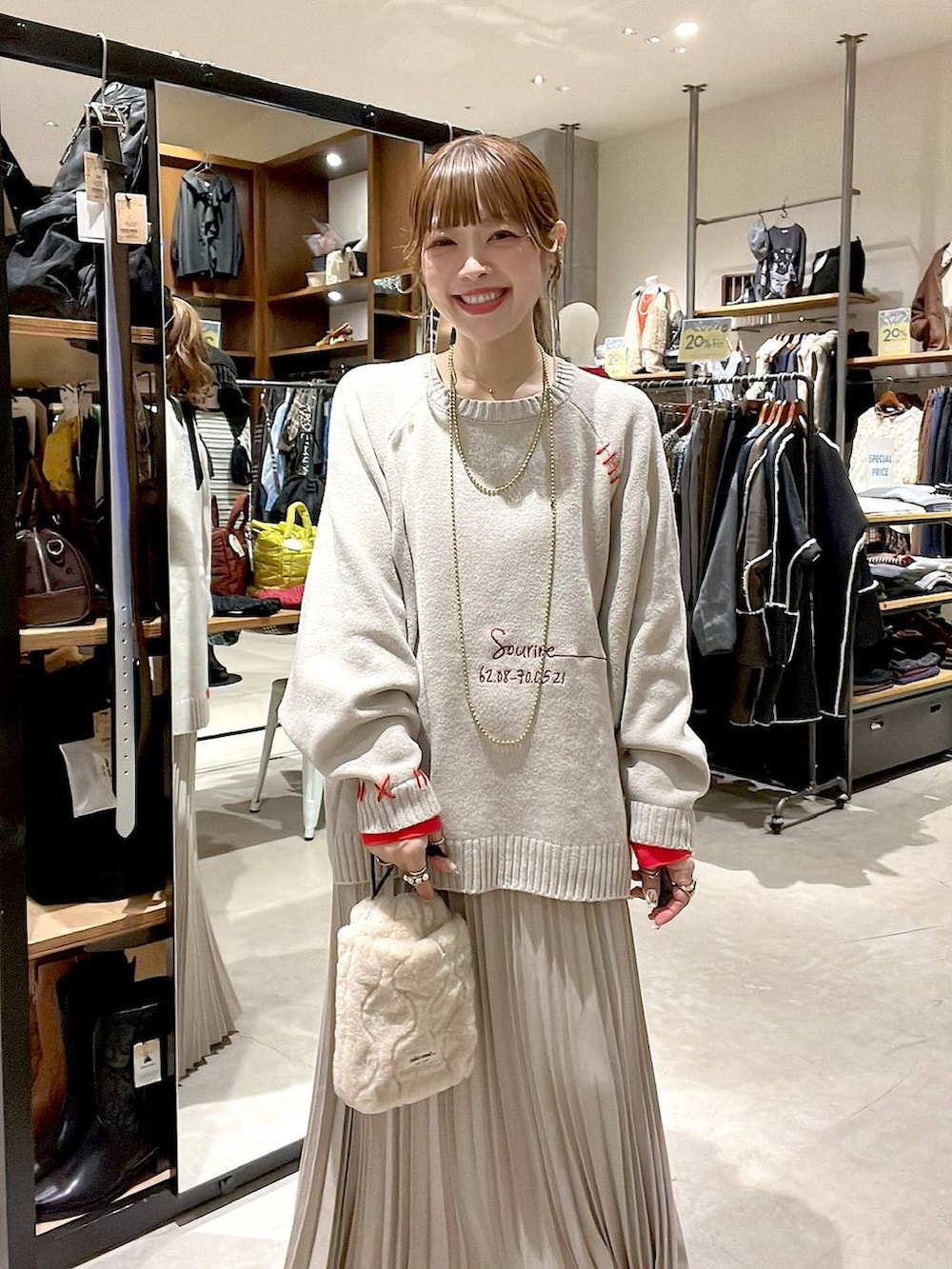 ベージュ系のスカート、ベージュ系のショルダーバッグ、イエロー系のネックレスを着用したレディースの秋コーディネートの8枚目の写真