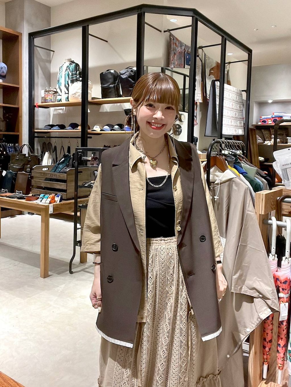 イエロー系のスカート、ブラウン系のベストを着用したレディースの夏コーディネートの5枚目の写真