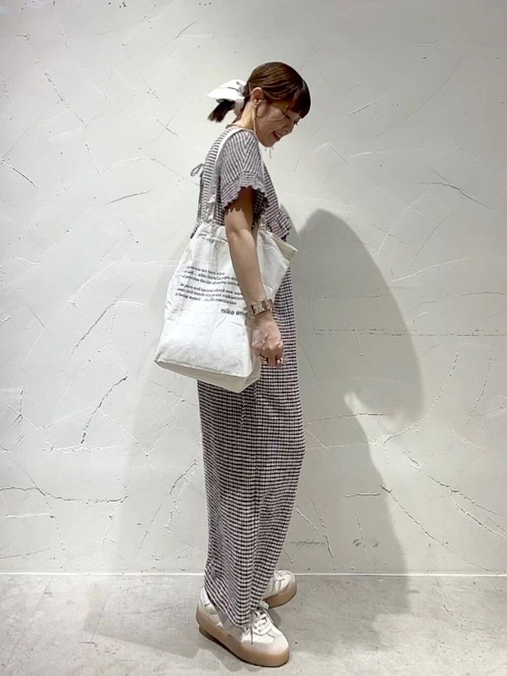 ベージュ系のトートバッグ、イエロー系のアナログ腕時計、ゴールド系のネックレスを着用したレディースの春コーディネートの4枚目の写真