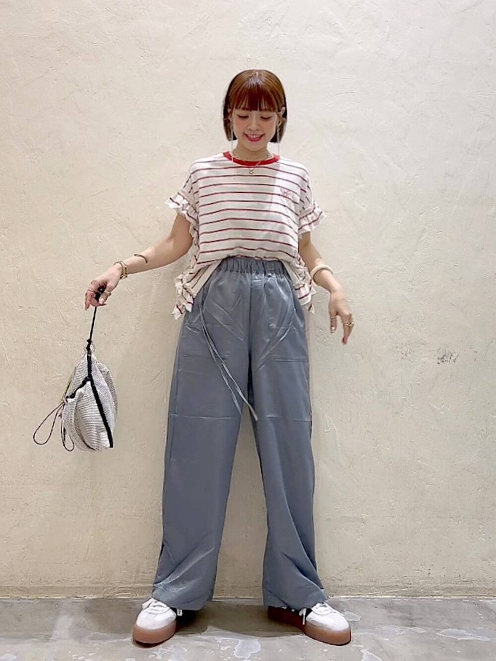 レッド系のTシャツ/カットソー、グレー系のショルダーバッグ、グレー系のその他パンツを着用したレディースの夏コーディネートの2枚目の写真