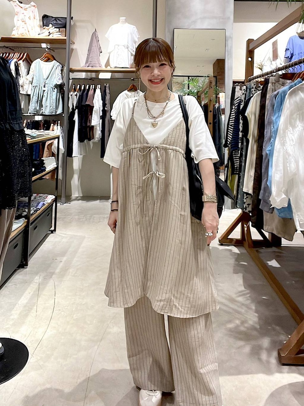 ブラック系のショルダーバッグ、ホワイト系のTシャツ/カットソー、ベージュ系のその他雑貨を着用したレディースの夏コーディネートの3枚目の写真