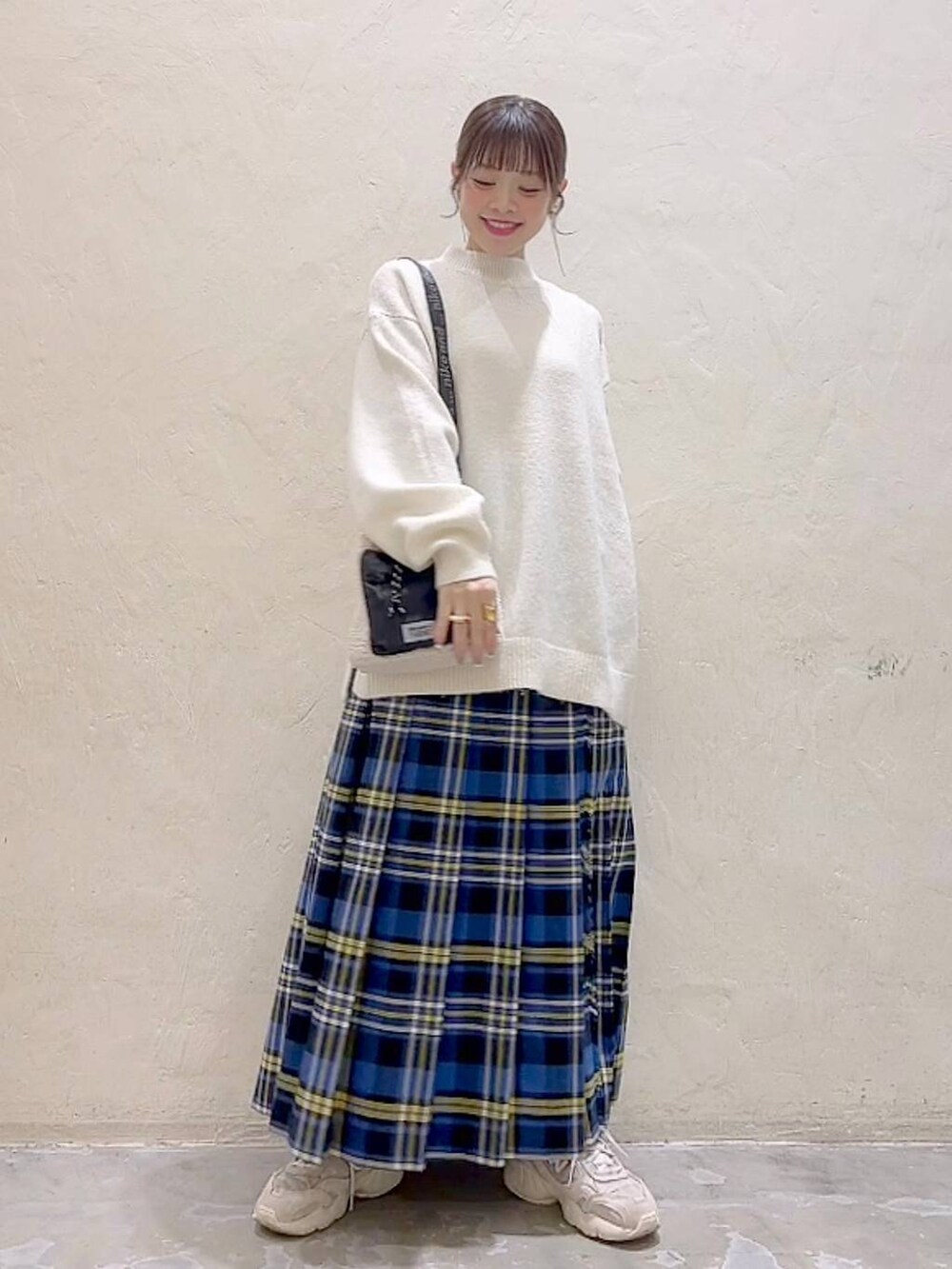 ブルー系のスカート、ホワイト系のニット/セーター、ベージュ系のショルダーバッグを着用したレディースの冬コーディネートの2枚目の写真