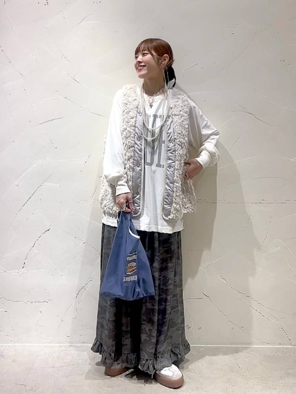 ベージュ系のベスト、その他のトートバッグ、グリーン系のスカートを着用したレディースの秋コーディネートの3枚目の写真