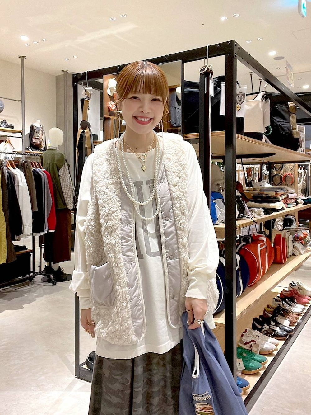 ベージュ系のベスト、その他のトートバッグ、グリーン系のスカートを着用したレディースの秋コーディネートの7枚目の写真