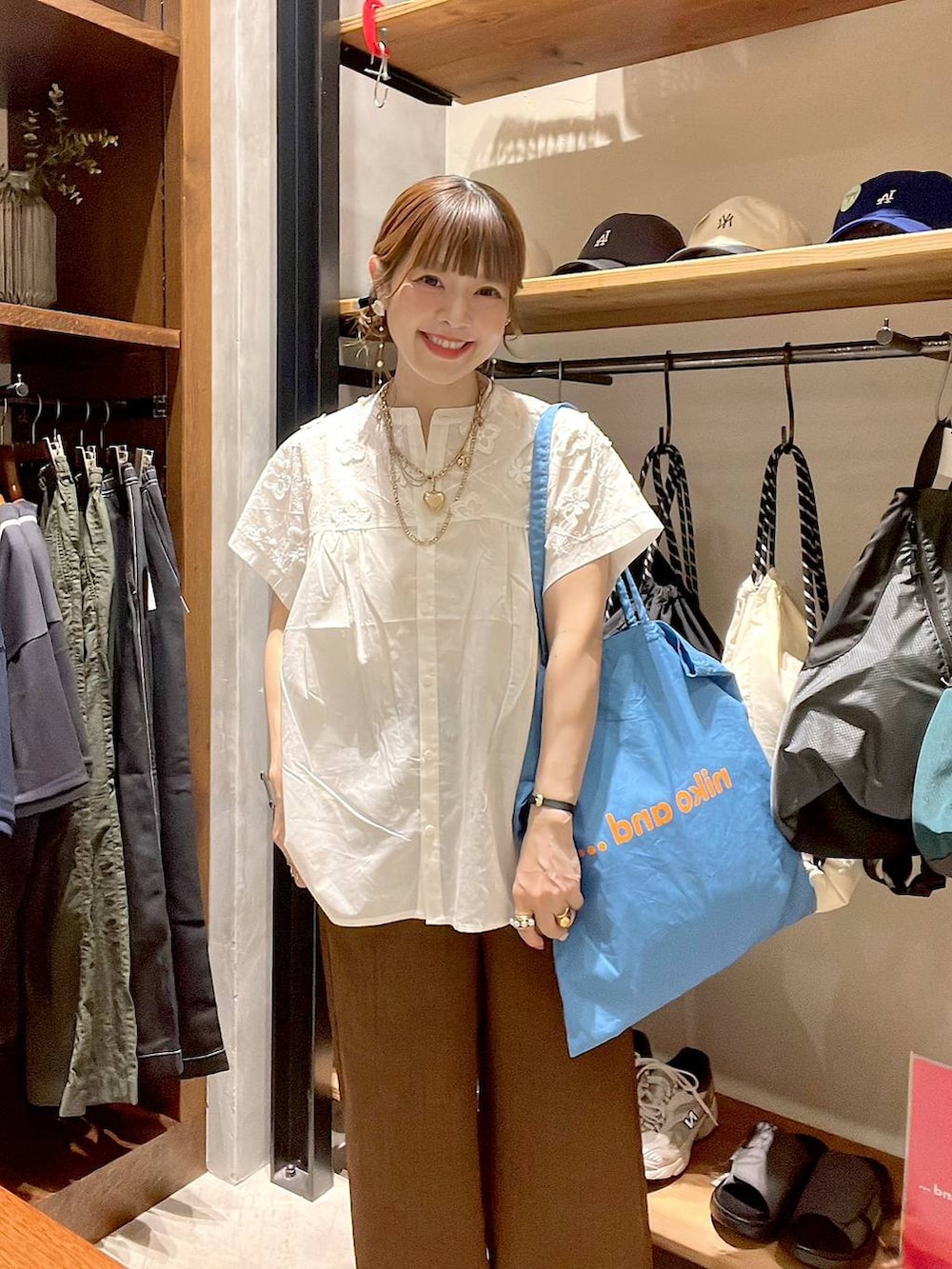 ブルー系のトートバッグ、ホワイト系のシャツ/ブラウス、ブラウン系のその他パンツを着用したレディースの夏コーディネートの2枚目の写真