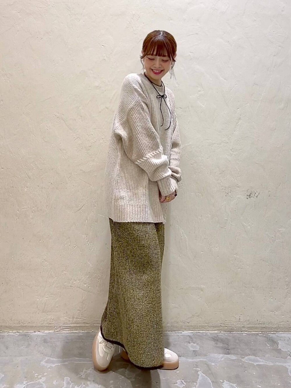 イエロー系のスカート、ベージュ系のニット/セーター、ブラック系のチョーカーを着用したレディースの秋コーディネートの3枚目の写真