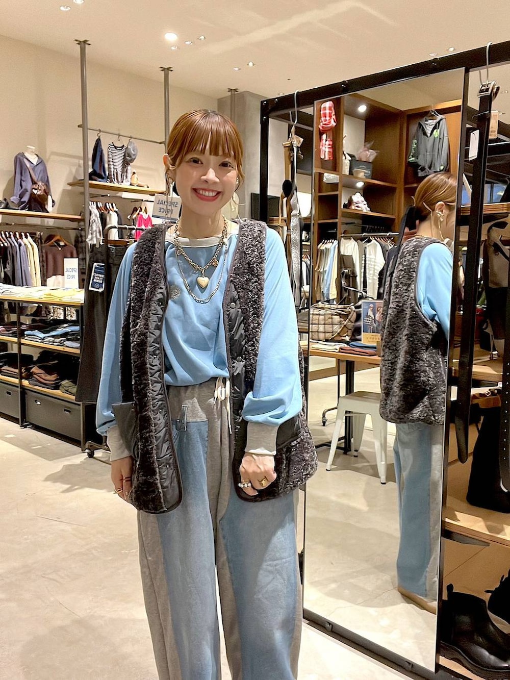 グレー系のベスト、グレー系のデニムパンツ、ゴールド系のネックレスを着用したレディースの秋コーディネートの7枚目の写真
