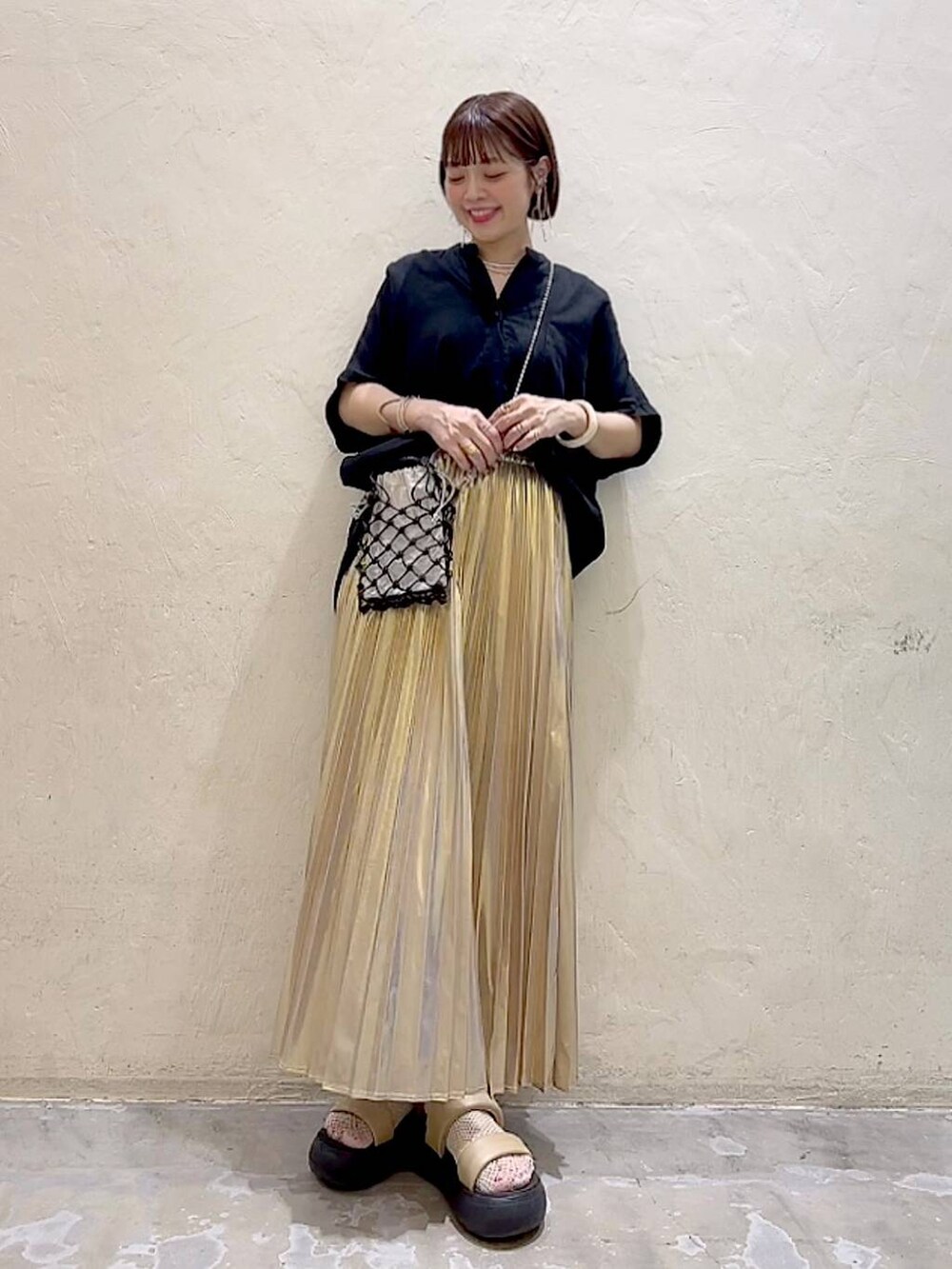 ブラック系のショルダーバッグ、イエロー系のサンダル、イエロー系のスカートを着用したレディースの夏コーディネートの6枚目の写真