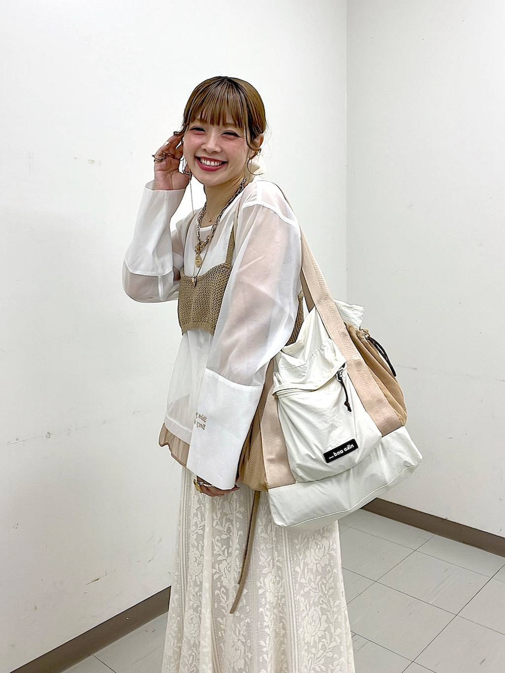 ベージュ系のスニーカー、ベージュ系のトートバッグ、ベージュ系のスカートを着用したレディースの冬コーディネートの2枚目の写真