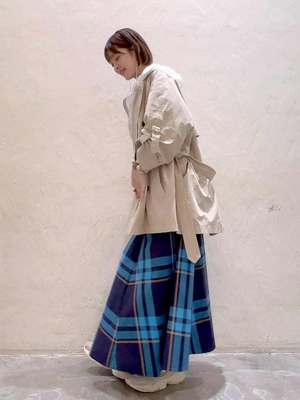 ベージュ系のトレンチコート、ベージュ系のキャミソール、ホワイト系のマウンテンパーカーを着用したレディースの春コーディネートの6枚目の写真