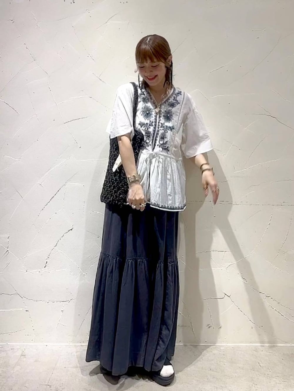 グレー系のスカート、ホワイト系のシャツ/ブラウス、ブラック系のトートバッグを着用したレディースの春コーディネートの9枚目の写真