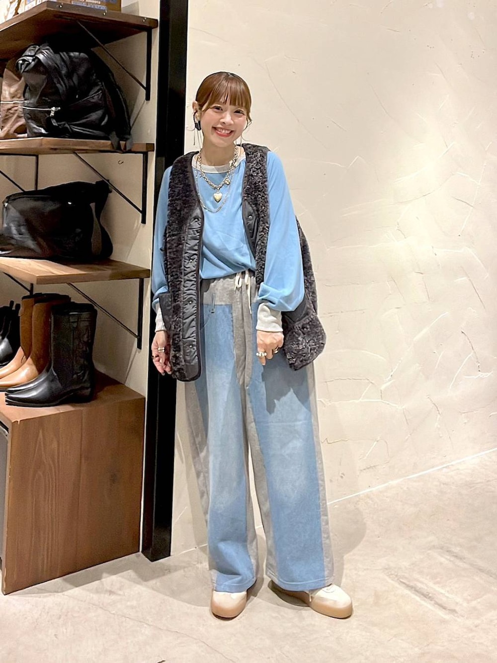 グレー系のベスト、グレー系のデニムパンツ、ゴールド系のネックレスを着用したレディースの秋コーディネートの3枚目の写真