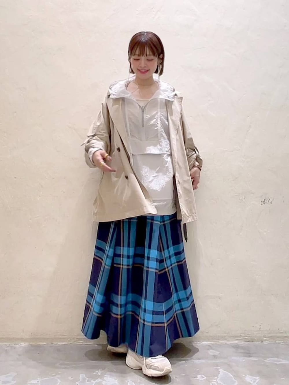 ベージュ系のトレンチコート、ベージュ系のキャミソール、ホワイト系のマウンテンパーカーを着用したレディースの春コーディネートの3枚目の写真