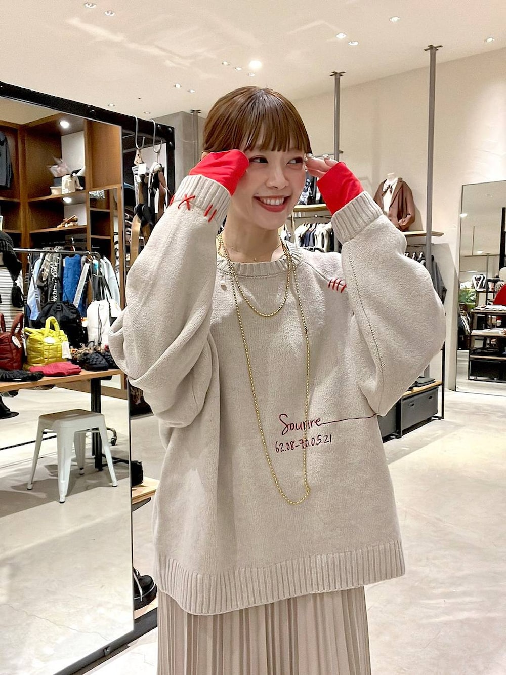 ベージュ系のスカート、ベージュ系のショルダーバッグ、イエロー系のネックレスを着用したレディースの秋コーディネートの7枚目の写真