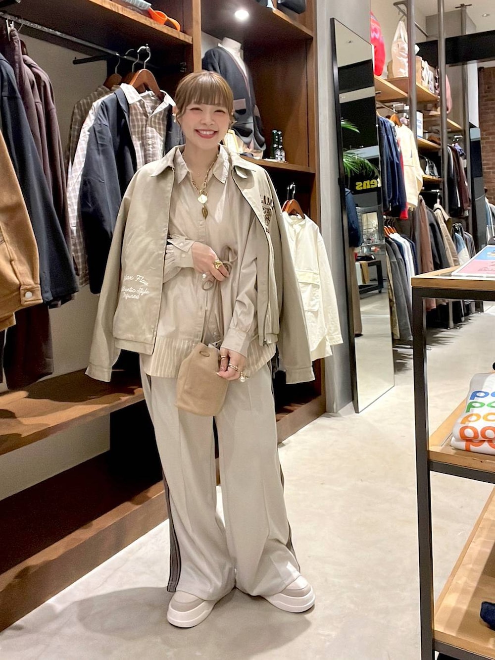 ベージュ系のシャツ/ブラウス、ベージュ系のショルダーバッグ、ベージュ系のスニーカーを着用したレディースの冬コーディネートの2枚目の写真