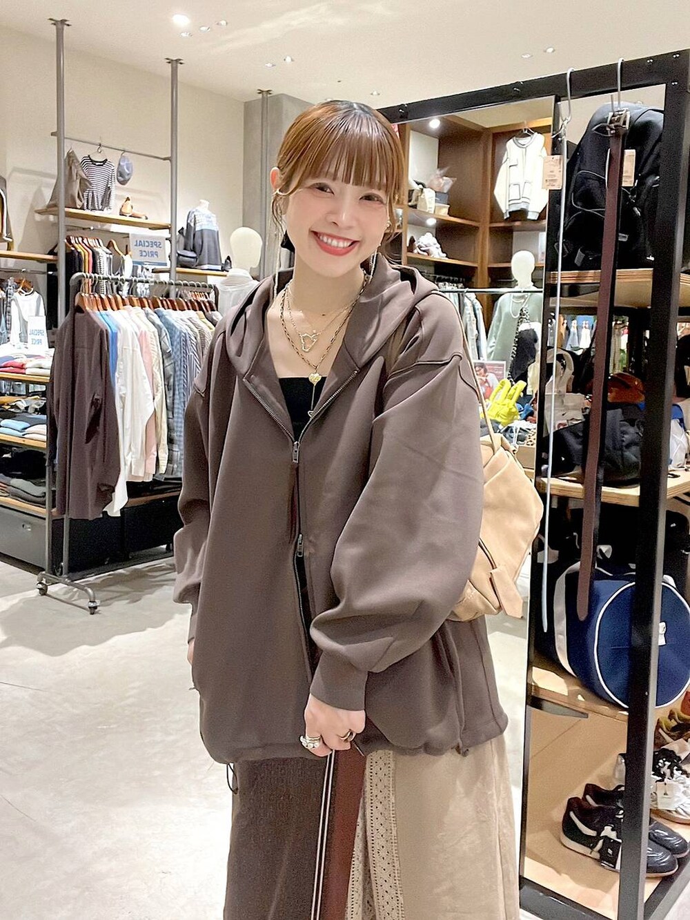 イエロー系のスカート、ブラウン系のパーカー、ベージュ系のボストンバッグを着用したレディースの秋コーディネートの2枚目の写真