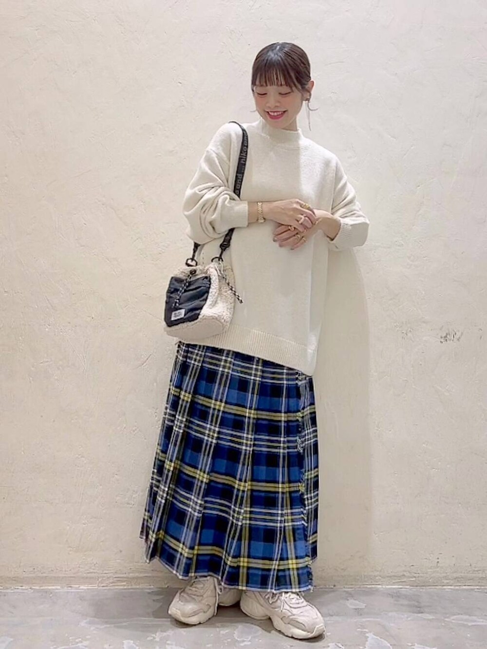 ブルー系のスカート、ホワイト系のニット/セーター、ベージュ系のショルダーバッグを着用したレディースの冬コーディネートの6枚目の写真