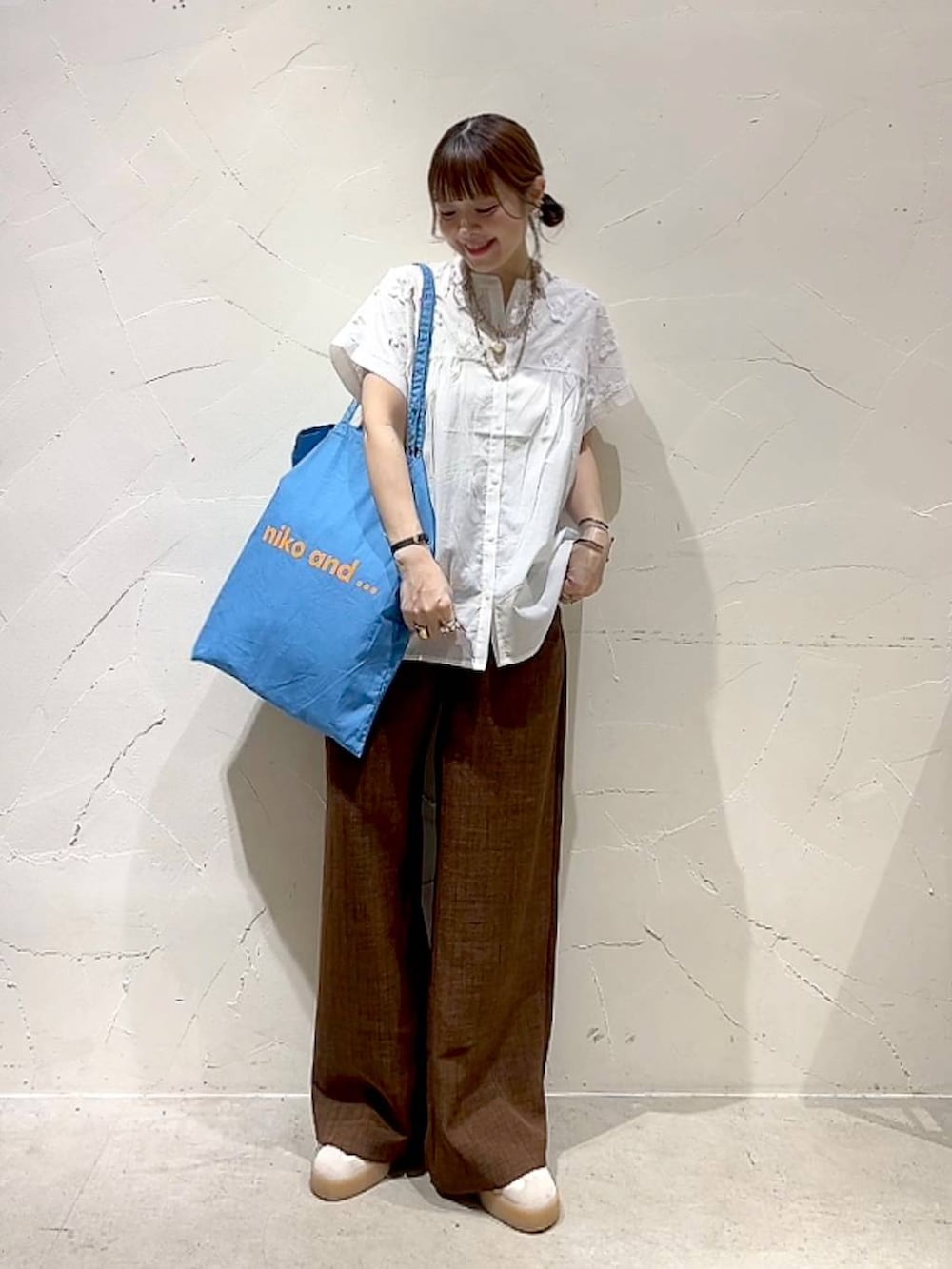 ブルー系のトートバッグ、ホワイト系のシャツ/ブラウス、ブラウン系のその他パンツを着用したレディースの夏コーディネートの3枚目の写真