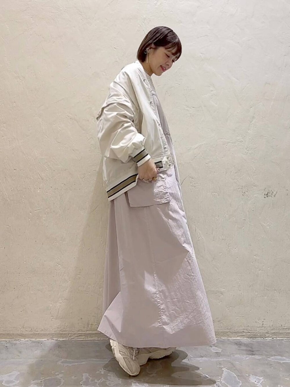 ベージュ系のスタジャン、ベージュ系のワンピース、ホワイト系のTシャツ/カットソーを着用したレディースの春コーディネートの3枚目の写真