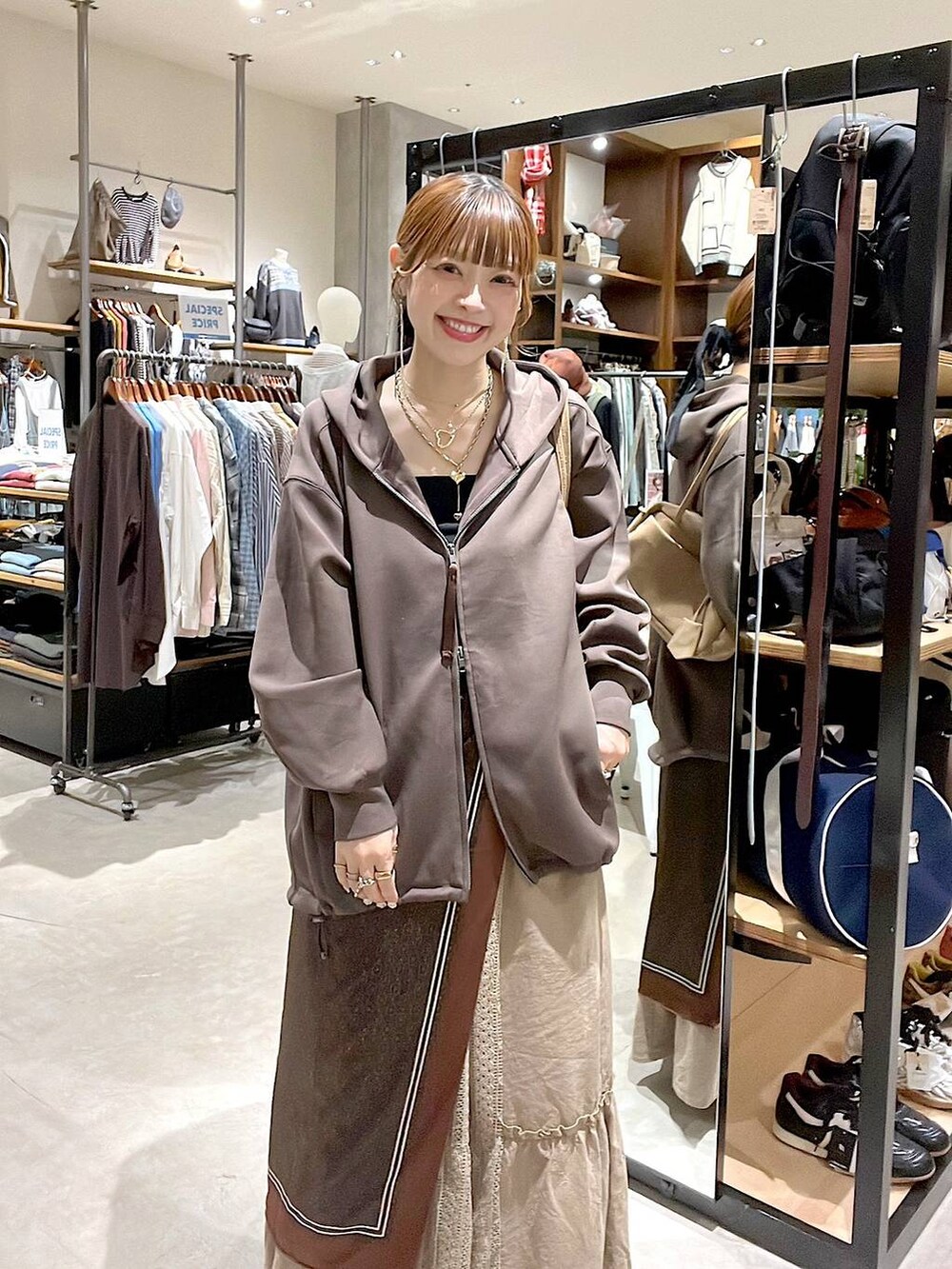 イエロー系のスカート、ブラウン系のパーカー、ベージュ系のボストンバッグを着用したレディースの秋コーディネートの4枚目の写真