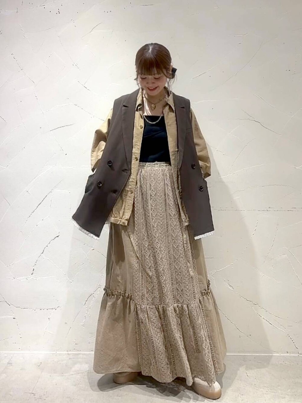 イエロー系のスカート、ブラウン系のベストを着用したレディースの夏コーディネートの4枚目の写真