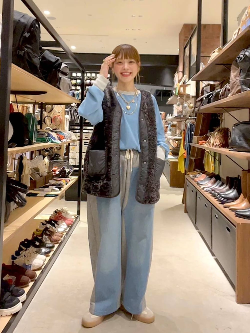 グレー系のベスト、グレー系のデニムパンツ、ゴールド系のネックレスを着用したレディースの秋コーディネートの2枚目の写真