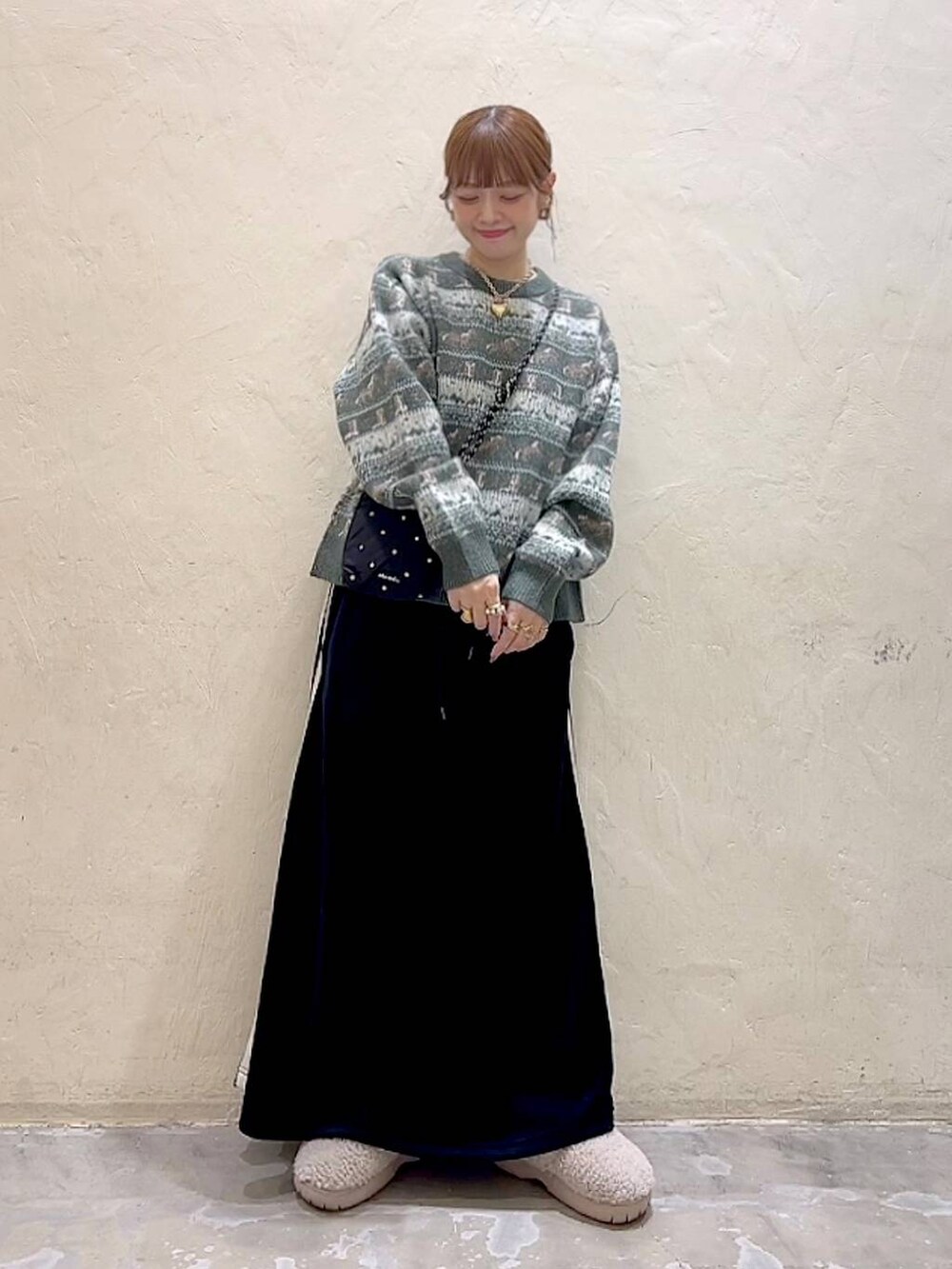 ブラック系のショルダーバッグ、ベージュ系のスリッポン、ブラック系のスカートを着用したレディースの冬コーディネートの2枚目の写真