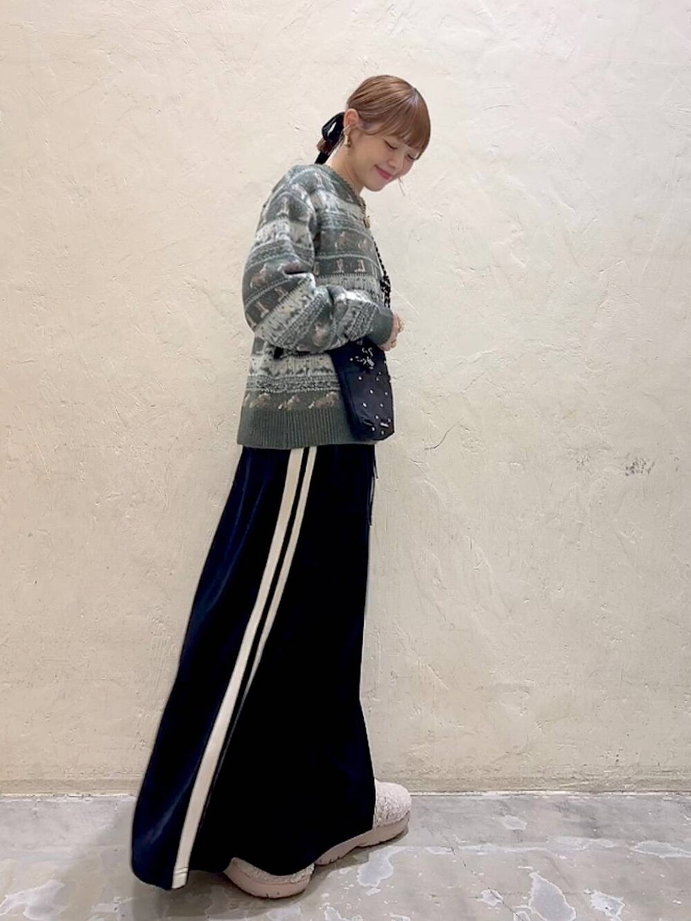 ブラック系のショルダーバッグ、ベージュ系のスリッポン、ブラック系のスカートを着用したレディースの冬コーディネートの5枚目の写真