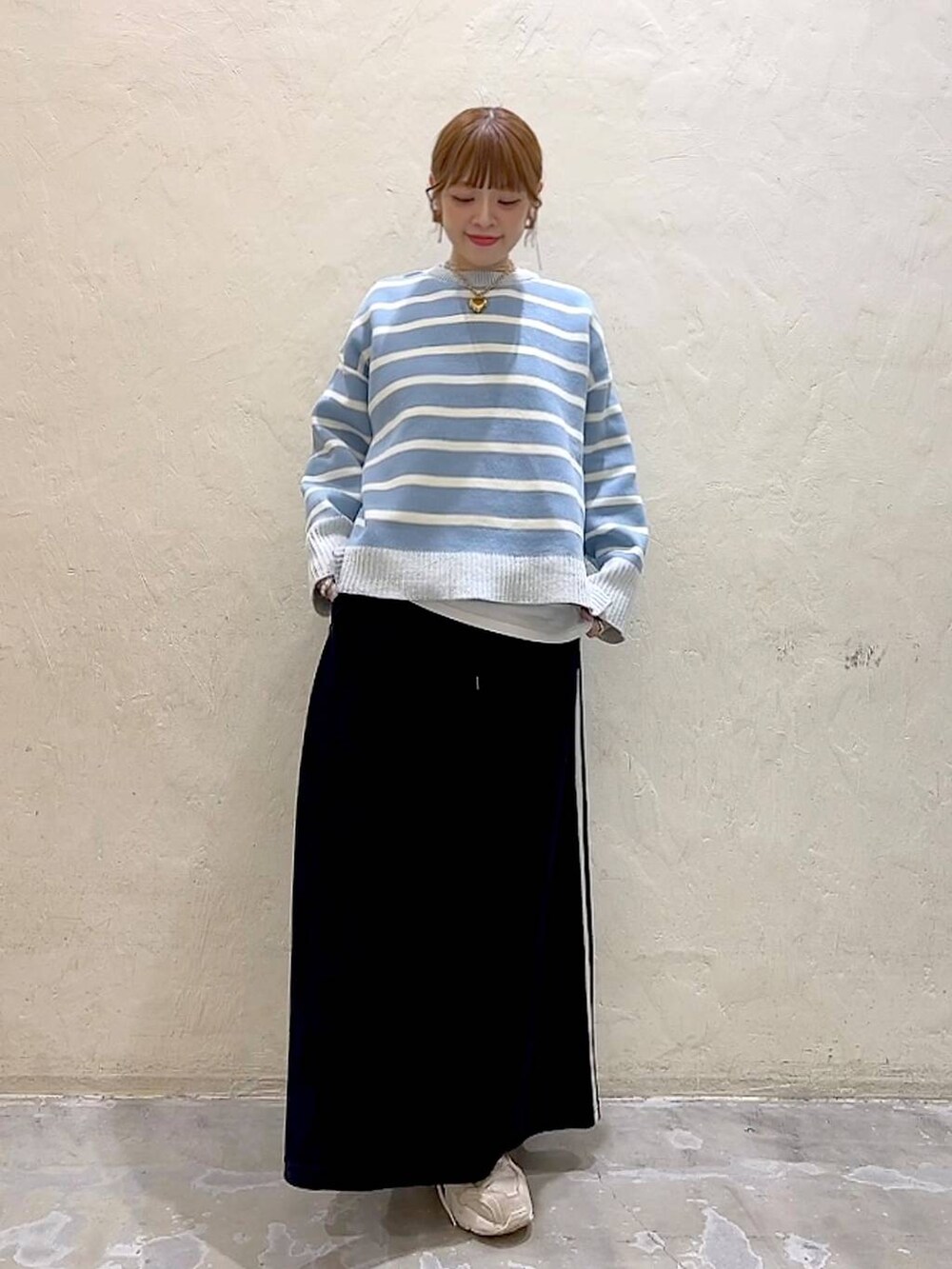 ホワイト系のTシャツ/カットソー、ブラック系のスカート、ベージュ系のニット/セーターを着用したレディースの冬コーディネートの2枚目の写真