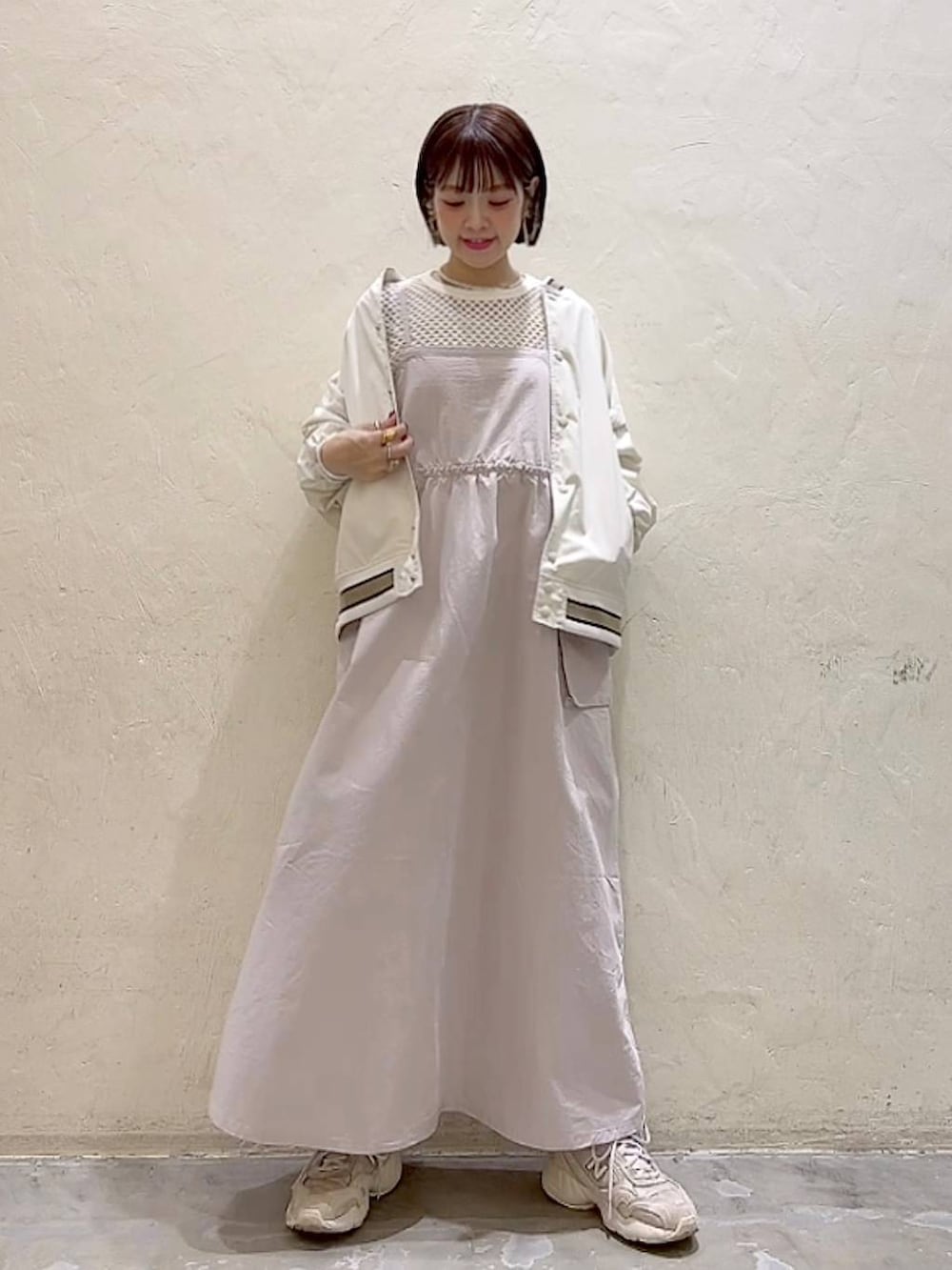 ベージュ系のスタジャン、ベージュ系のワンピース、ホワイト系のTシャツ/カットソーを着用したレディースの春コーディネートの2枚目の写真