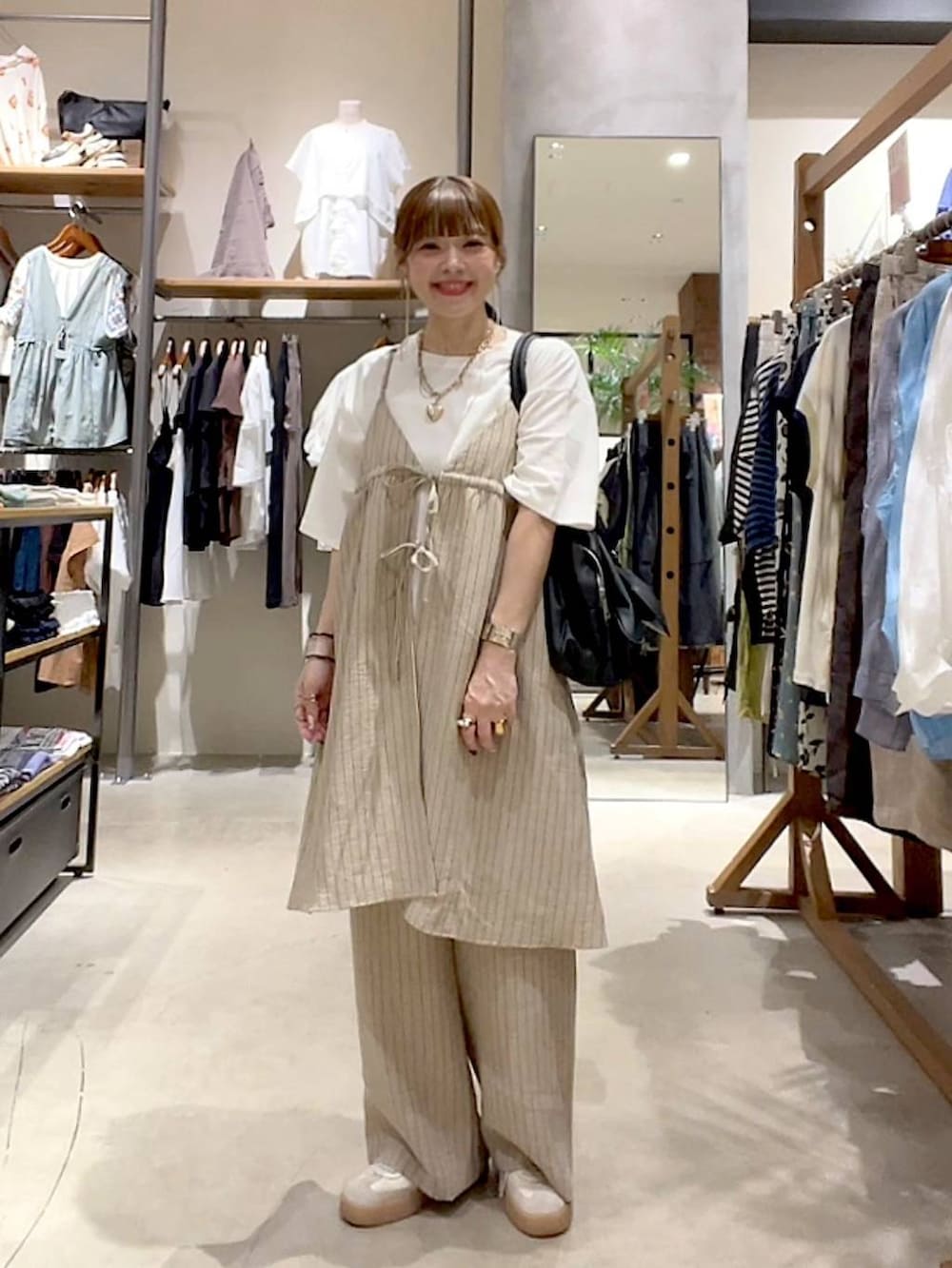 ブラック系のショルダーバッグ、ホワイト系のTシャツ/カットソー、ベージュ系のその他雑貨を着用したレディースの夏コーディネートの2枚目の写真