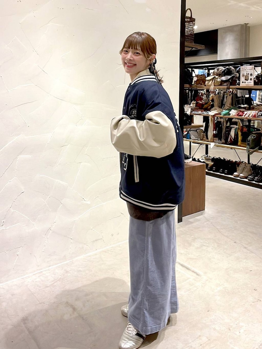 ゴールド系のスニーカー、ブルー系のスカート、ブルー系のブルゾンを着用したレディースの秋コーディネートの6枚目の写真